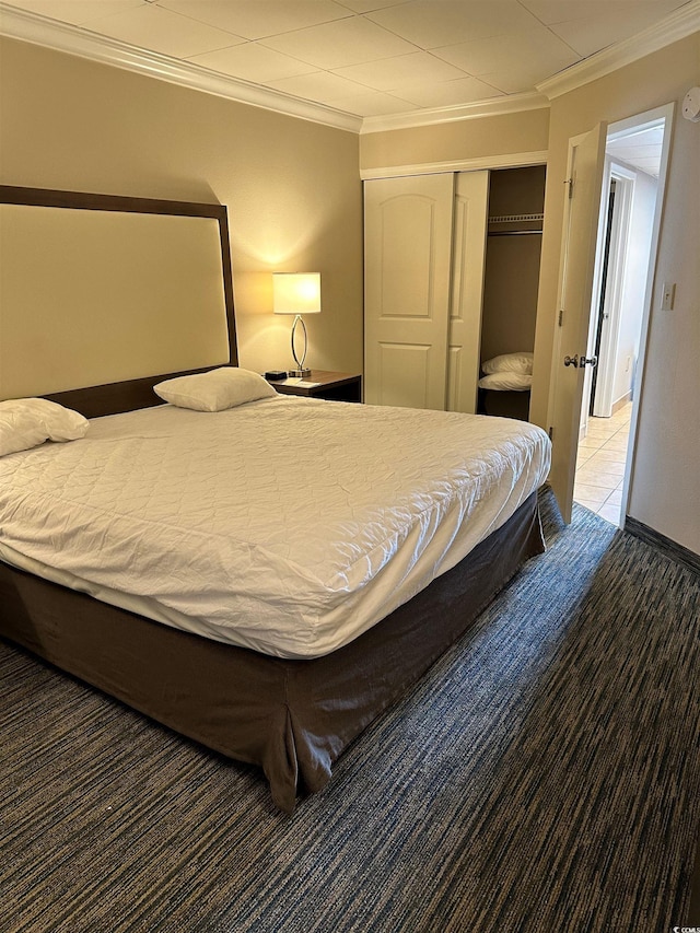 carpeted bedroom featuring tile patterned flooring, crown molding, and a closet