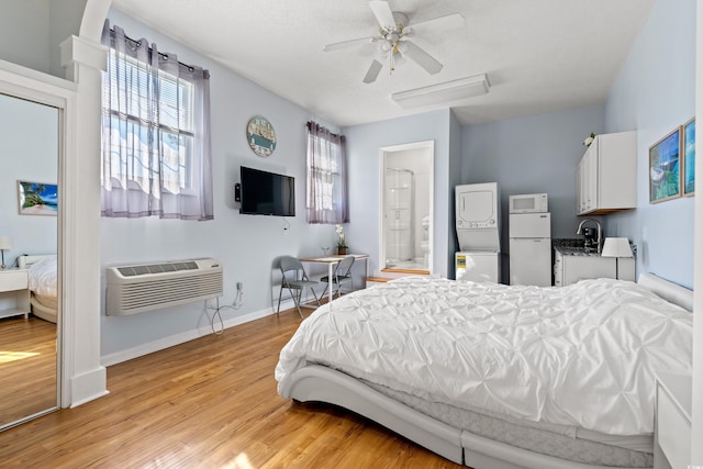 3763 Annandale Dr, Myrtle Beach, SC 29577 - bedroom featuring a wall mounted AC, refrigerator, stacked washing maching and dryer, light wood finished floors, and baseboards
