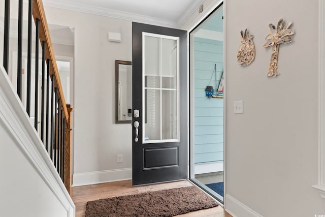 foyer entrance with ornamental molding, stairs, baseboards, and wood finished floors