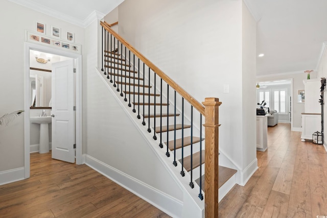 stairs with crown molding, baseboards, wood-type flooring, and ceiling fan