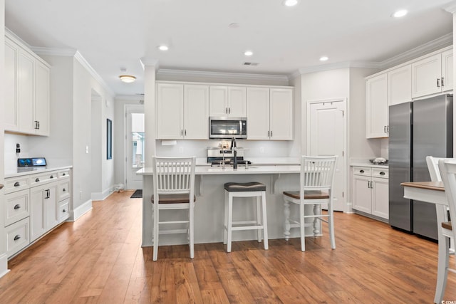 kitchen featuring light countertops, white cabinets, ornamental molding, and stainless steel appliances