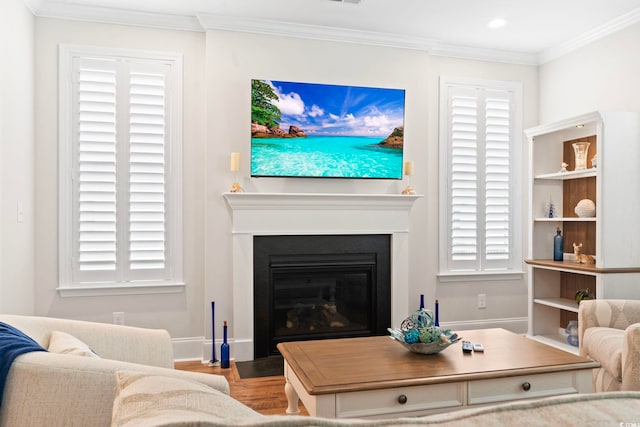 living area featuring baseboards, wood finished floors, a glass covered fireplace, and crown molding