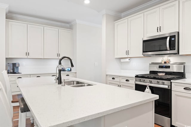 kitchen with a kitchen bar, ornamental molding, a center island with sink, a sink, and stainless steel appliances