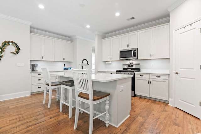 kitchen featuring visible vents, ornamental molding, appliances with stainless steel finishes, and a sink