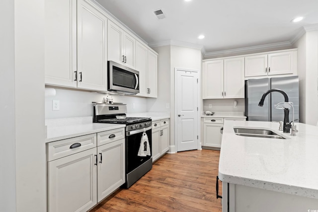 kitchen with visible vents, ornamental molding, appliances with stainless steel finishes, and a sink