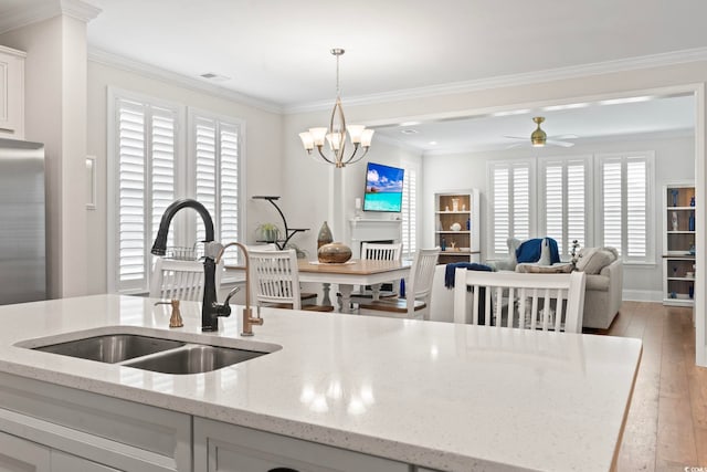 kitchen with visible vents, ornamental molding, light wood-style flooring, white cabinets, and a sink