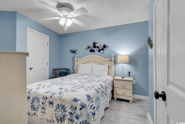 bedroom with baseboards, ceiling fan, a textured ceiling, and light wood-style floors