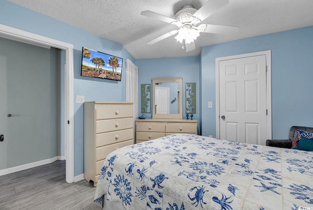 bedroom featuring a ceiling fan, baseboards, light wood finished floors, and a textured ceiling