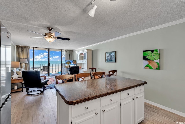 kitchen with dark countertops, light wood-style flooring, a ceiling fan, and open floor plan