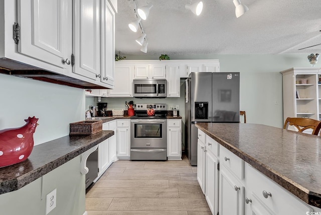 kitchen featuring dark countertops, appliances with stainless steel finishes, wood tiled floor, and white cabinetry