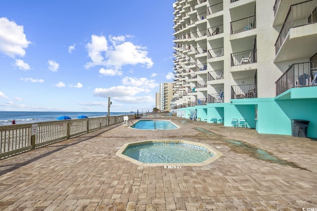 view of pool featuring a community hot tub and a water view