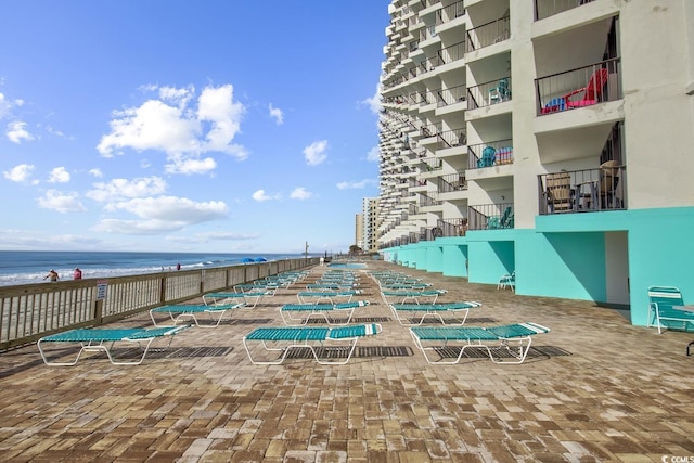 exterior space featuring a beach view, stairway, and a water view