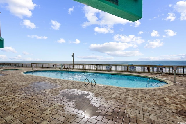 pool featuring a patio area and a water view