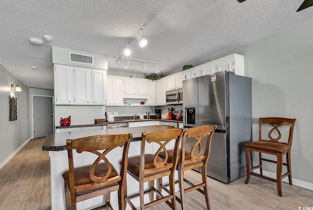 kitchen featuring dark countertops, light wood-type flooring, visible vents, and stainless steel appliances