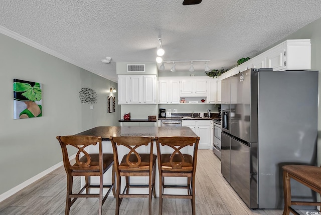 kitchen with visible vents, wood tiled floor, appliances with stainless steel finishes, white cabinetry, and dark countertops