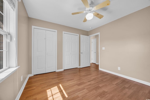 4938 Trooper Ln, Loris, SC 29569 - unfurnished bedroom with multiple closets, light wood-style floors, baseboards, and a ceiling fan