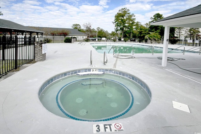 pool with a patio, a hot tub, and fence