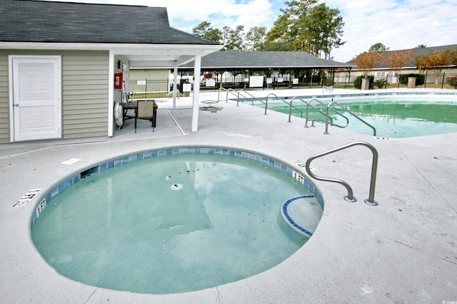 community pool featuring fence, a community hot tub, and a patio area