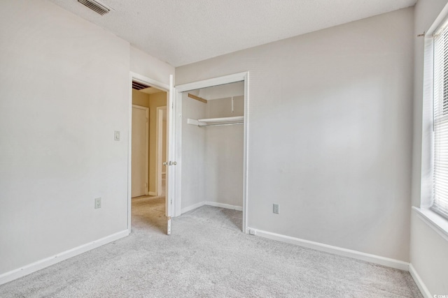 unfurnished bedroom with carpet flooring, baseboards, visible vents, and a textured ceiling