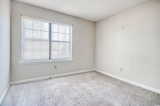 carpeted spare room with a textured ceiling and baseboards