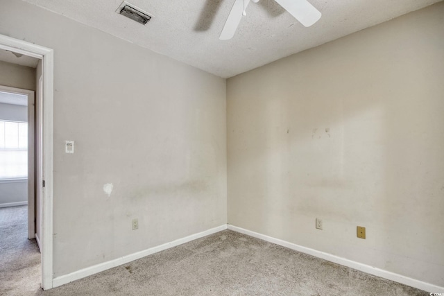 carpeted empty room with a textured ceiling, a ceiling fan, visible vents, and baseboards