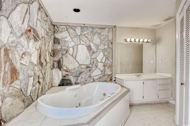 full bathroom featuring vanity, visible vents, a closet, a textured ceiling, and a jetted tub