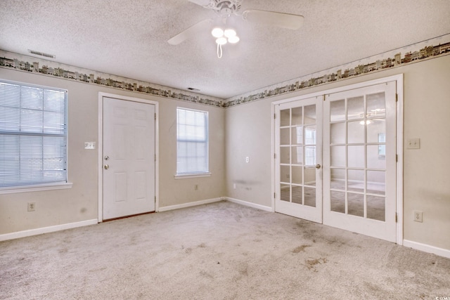 carpeted spare room with baseboards, visible vents, a textured ceiling, and a ceiling fan