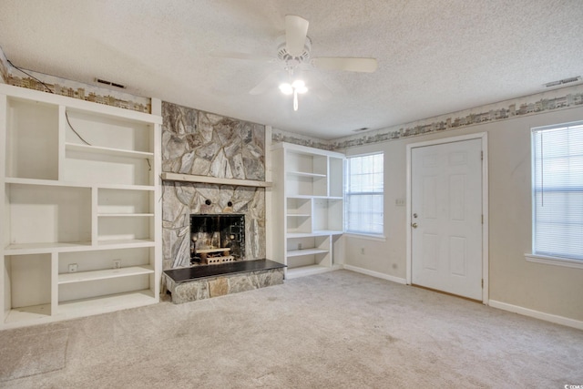 unfurnished living room with a wealth of natural light, a textured ceiling, carpet, and a ceiling fan