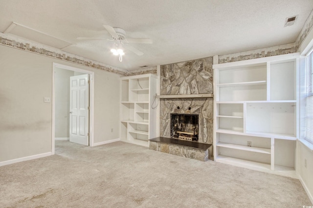 unfurnished living room featuring visible vents, a textured ceiling, a stone fireplace, and ceiling fan