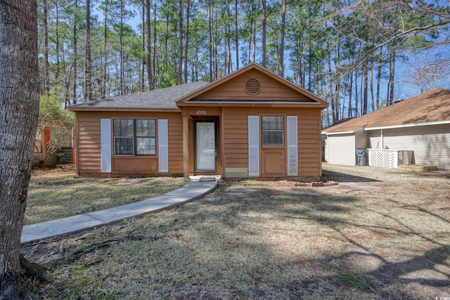 view of front of home featuring a front yard and a shingled roof