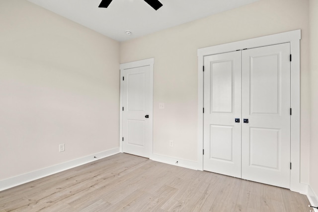 unfurnished bedroom with a closet, light wood-style flooring, baseboards, and ceiling fan