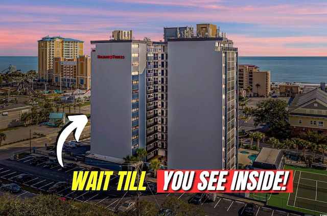 property at dusk with a water view and a city view