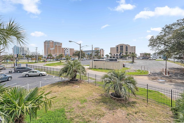 view of home's community featuring a view of city, uncovered parking, and fence