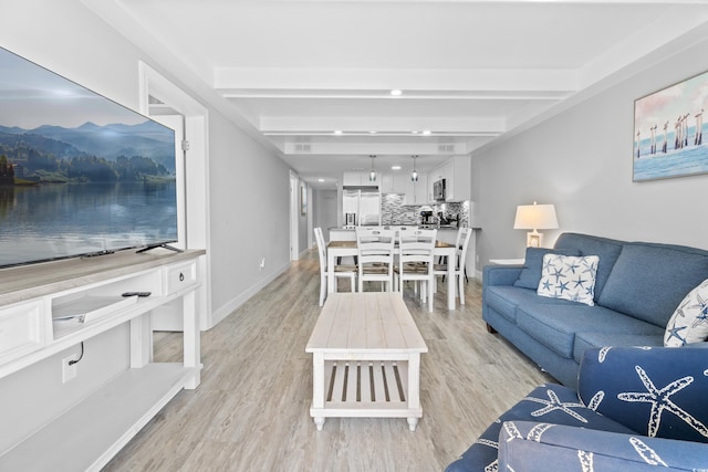 living room with baseboards, beam ceiling, and light wood finished floors