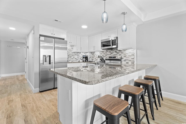 kitchen featuring visible vents, light wood finished floors, a peninsula, appliances with stainless steel finishes, and tasteful backsplash