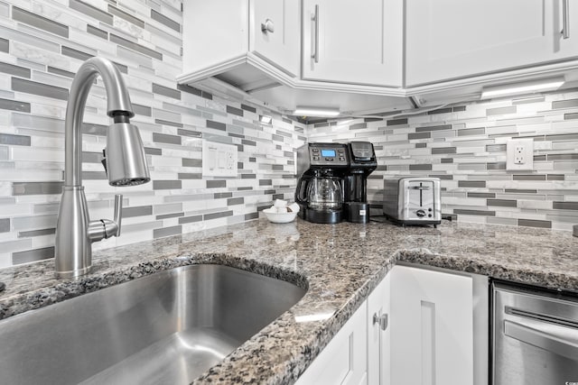 kitchen with tasteful backsplash, white cabinets, stone countertops, and a sink