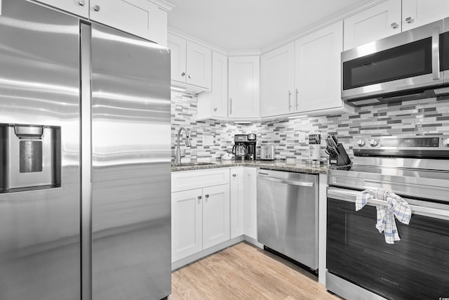 kitchen with stone counters, light wood-style flooring, a sink, stainless steel appliances, and white cabinetry