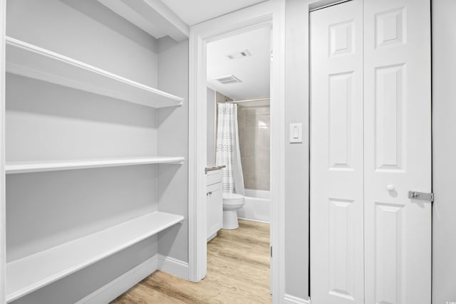 hallway featuring light wood-type flooring, baseboards, and visible vents