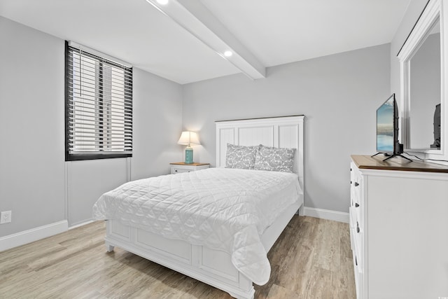 bedroom featuring beamed ceiling, baseboards, and light wood-style floors