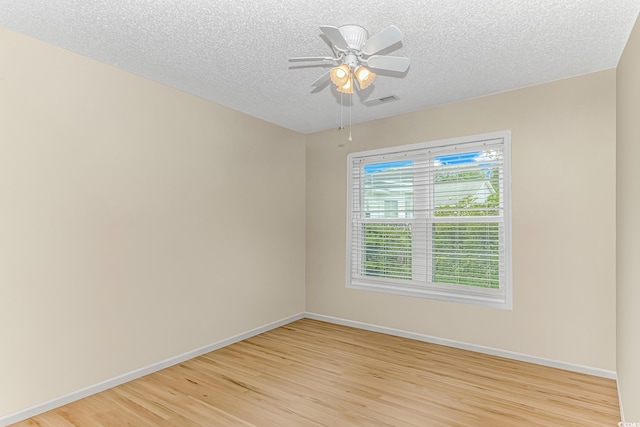 empty room with visible vents, light wood-style floors, baseboards, and ceiling fan