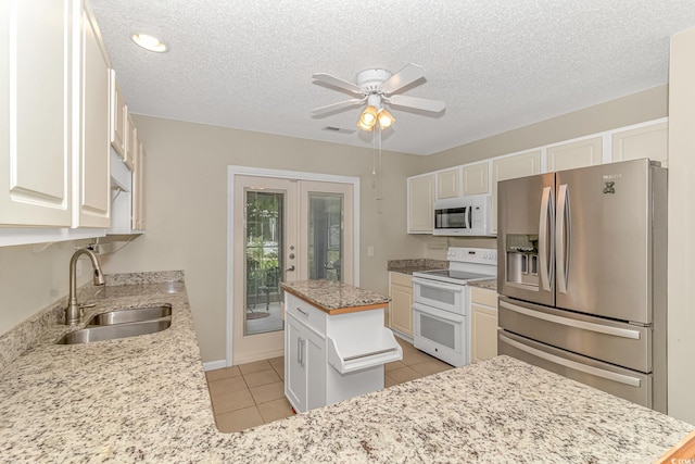 kitchen featuring white appliances, light tile patterned floors, visible vents, ceiling fan, and a sink