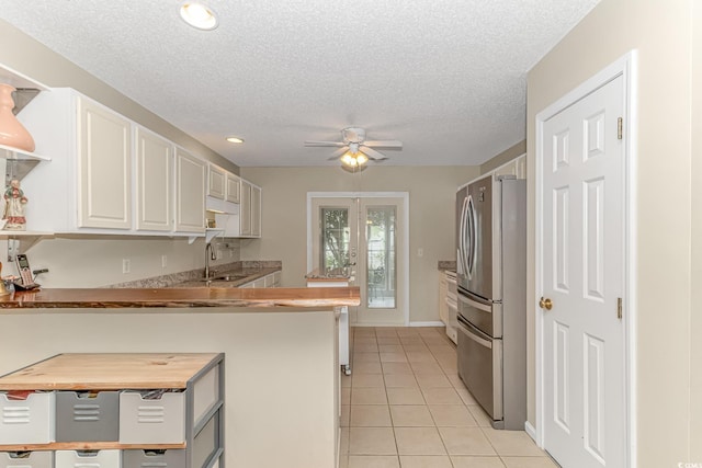 kitchen with ceiling fan, freestanding refrigerator, light tile patterned flooring, white cabinets, and a sink