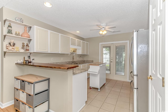 kitchen featuring open shelves, freestanding refrigerator, a sink, ceiling fan, and french doors