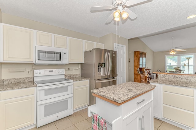 kitchen featuring white appliances, a ceiling fan, a kitchen island, light tile patterned flooring, and a textured ceiling