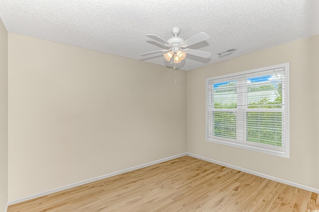 empty room with light wood finished floors, a textured ceiling, and baseboards