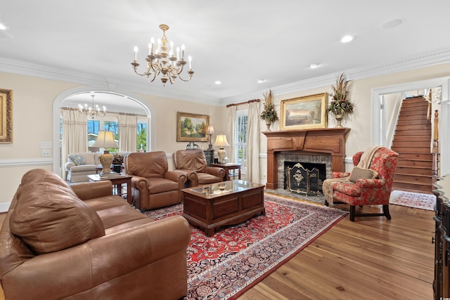 living room featuring wood finished floors, stairway, arched walkways, an inviting chandelier, and a fireplace