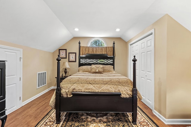 bedroom with vaulted ceiling, visible vents, baseboards, and wood finished floors