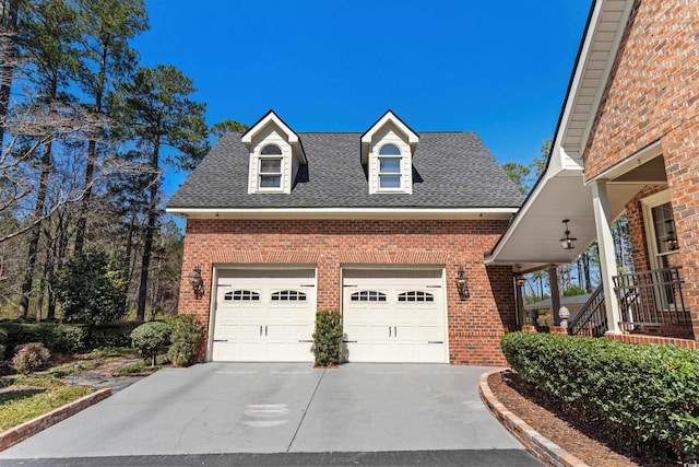 view of front facade with concrete driveway, brick siding, and a shingled roof