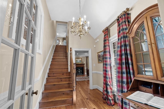 entryway featuring wood finished floors, lofted ceiling, stairs, french doors, and a chandelier