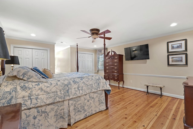 bedroom featuring ornamental molding, baseboards, multiple closets, and wood finished floors